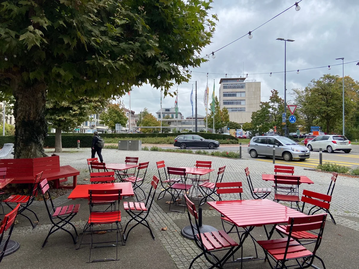 Rote Stühle der Weinbar im Zentrum von Uster, dahinter das Stadthaus.
